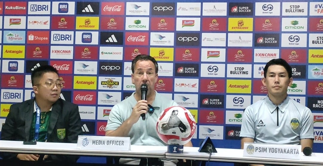 Pelatih PSIM Yogyakarta, Jean-Paul van Gastel (pegang mic), bersama pemainnya Yusaku Yamadera (abu-abu) pada sesi jumpa pers usai lawan Persebaya Surabaya di Stadion GBT, Surabaya, 8 Agustus 2025. (PSSI Pers)